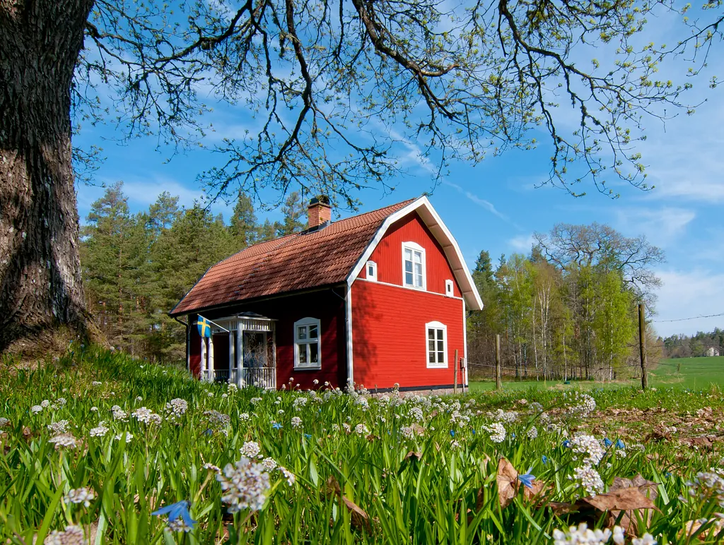 Stämningsfullt rött hus på sommaren vid en grön äng